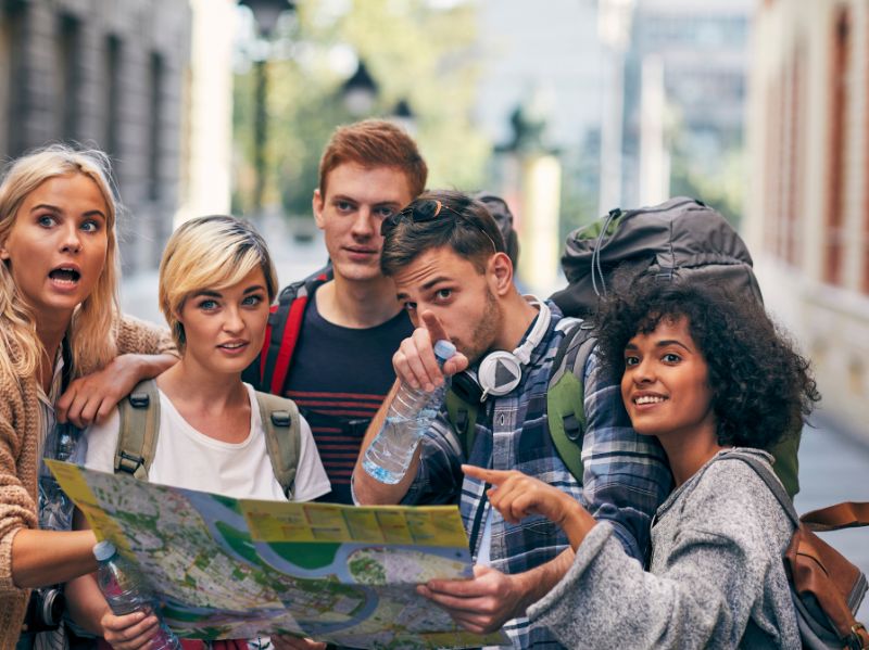 International travelers using a map and exploring a new city, stress the importance and excitement when you learn Portuguese online before traveling.